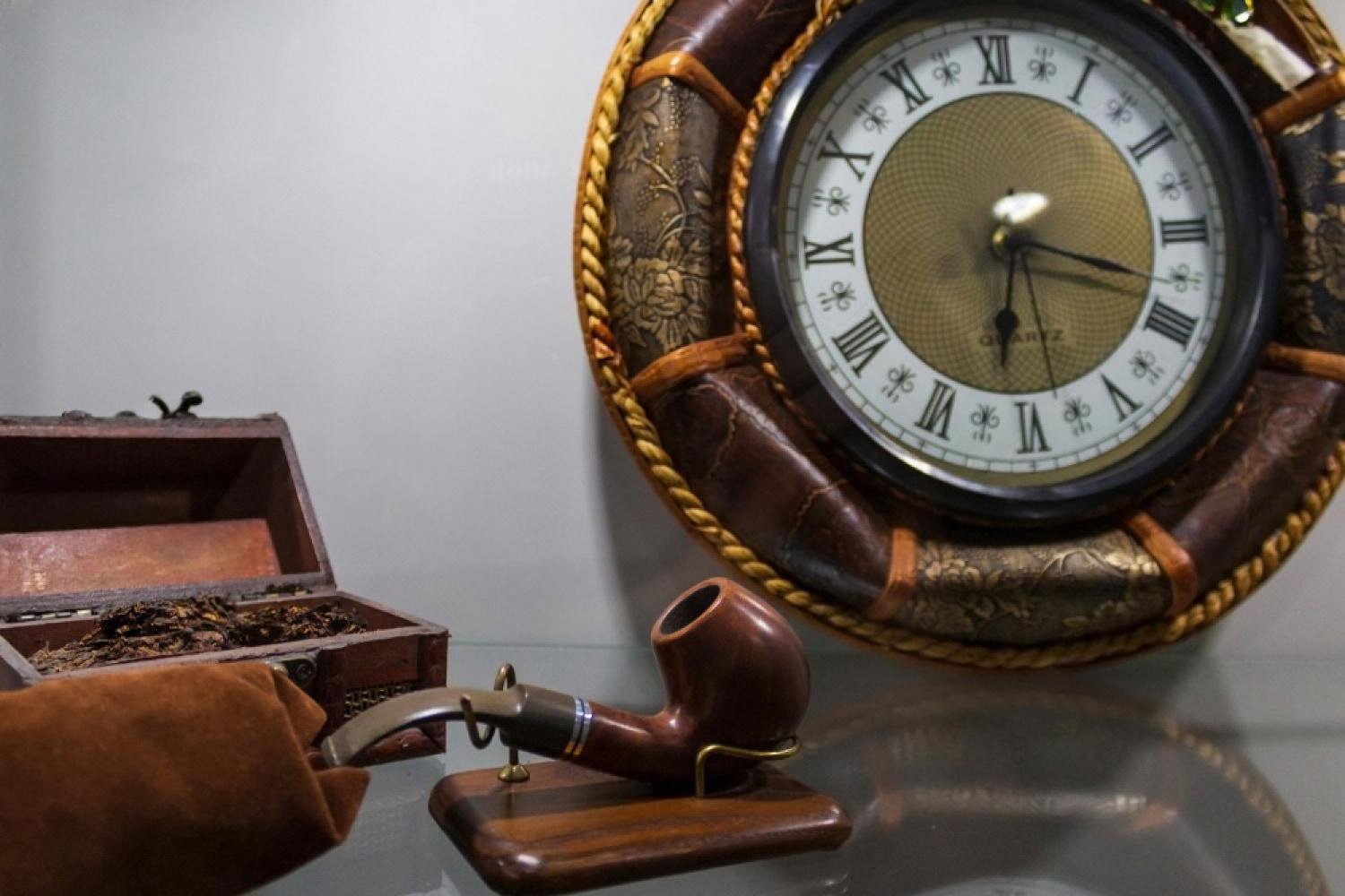 Vintage smoking pipe next to an antique clock representing the history of tobacco use